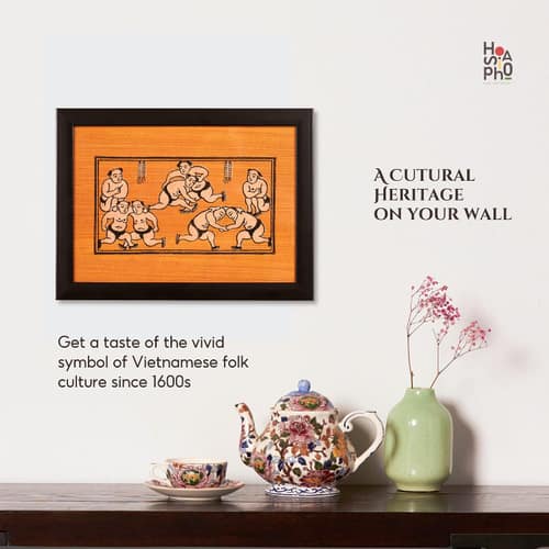 Framed Dong Ho woodcut of wrestlers hung above a console table, beside a floral teapot and a vase — “a cultural heritage on your wall”.